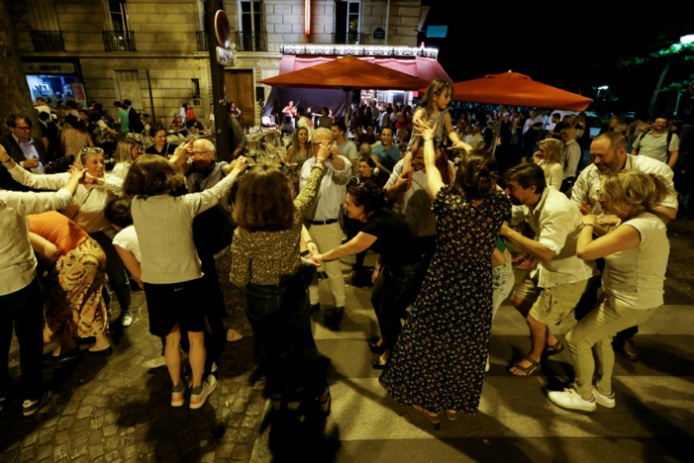 Des personnes dansent dans une rue de Paris pendant la fête de la musique, le 21 juin 2025 ( AFP / Ludovic MARIN )