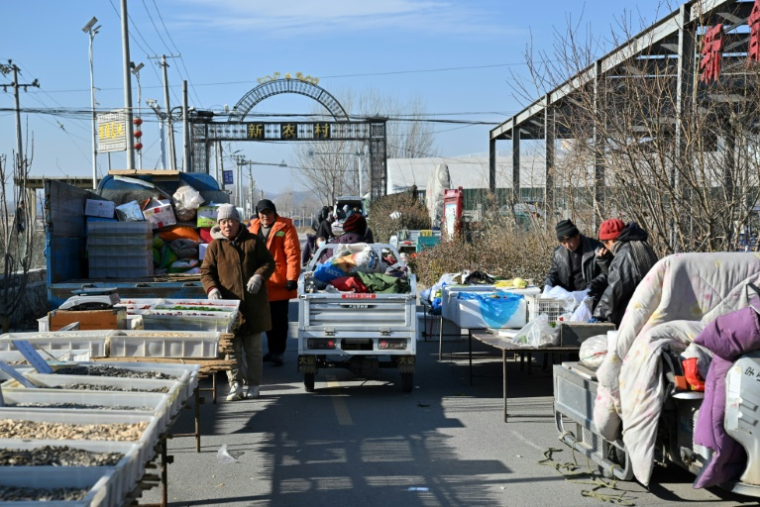 Des habitants chaudement vêtus sur un marché de la ville chinoise de Baoding, dans le district de Xushui à une centaine de kilomètres de Pékin, où les autorités ont ordonné  de remplacer les poêles à charbon par des systèmes électriques ou au gaz, le 7 janvier 2026 ( AFP / Adek BERRY )