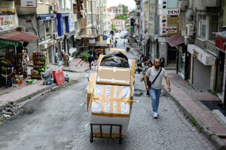 Un porteur pousse un chariot chargé de cartons dans le quartier de Laleli, à Istanbul, le 27 mai 2025 en Turquie ( AFP / Yasin AKGUL )