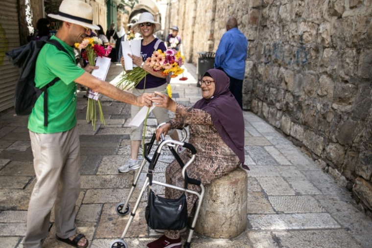 Des militants israéliens pour la paix distribuent des fleurs aux Palestiniens dans la vieille ville de Jérusalem lors des célébrations annuelles marquant l'occupation par Israël de la partie orientale de la ville sainte, le 26 mai 2025 ( AFP / John Wessels )