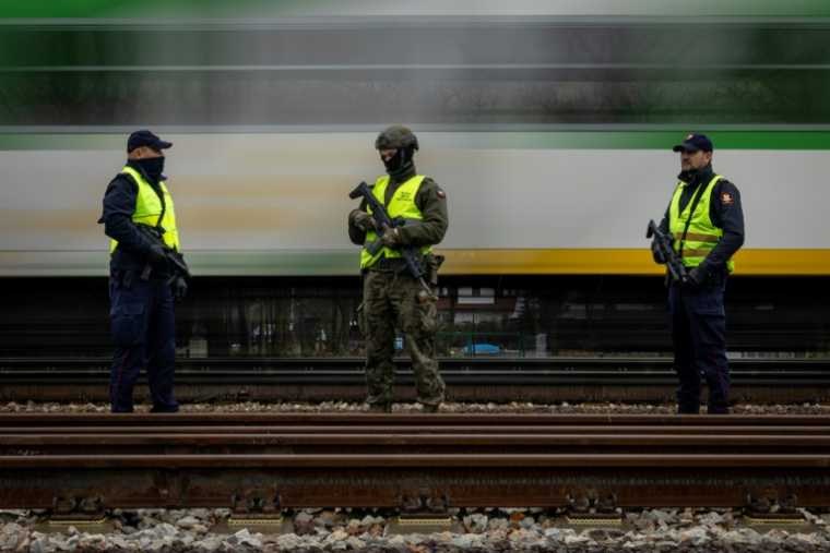 Des gardes de la sécurité ferroviaire armés et un soldat des Forces de défense territoriale patrouillent le long des voies ferrées dans la banlieue de Varsovie, le 27 novembre 2025 en Pologne ( AFP / Wojtek RADWANSKI )