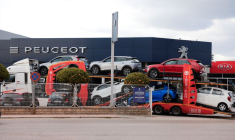 Un camion transporte des voitures neuves Peugeot et Kia