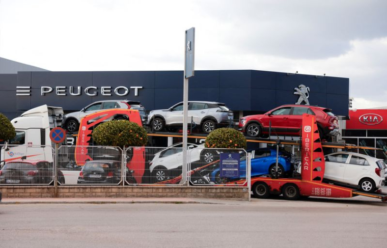 Un camion transporte des voitures neuves Peugeot et Kia