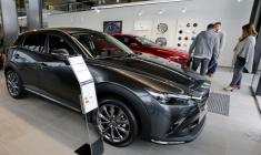 Des personnes regardent des voitures Mazda exposées dans une salle d'exposition d'un concessionnaire à Mérignac