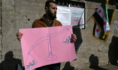 Un homme tient une pancarte lors d'une manifestation contre la hausse des prix de l'électricité en Syrie, à Damas le 29 janvier 2026, montrant d'un côté de la balance "le salaire" et de l'autre, à gauche, "la facture" ( AFP / LOUAI BESHARA )