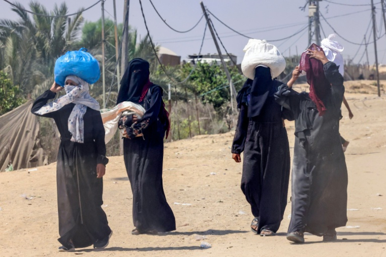 Des femmes portent des sacs d'aide humanitaire, à al-Mawasi, dans le sud de la bande de Gaza, le 28 juillet 2025 ( AFP / - )