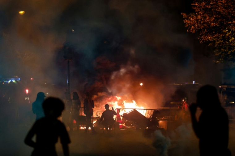 Des supporteurs du PSG près d'une barricade en feu après la victoire du PSG en Ligue des Champions, le 30 mai 2026 à Paris ( AFP / Kenzo TRIBOUILLARD )