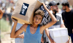 Un garçon porte une boîte d'aide humanitaire de la Fondation humanitaire de Gaza (GHF), venant d'un centre de distribution dans le centre de la bande de Gaza le 29 mai 2025 ( AFP / Eyad BABA )