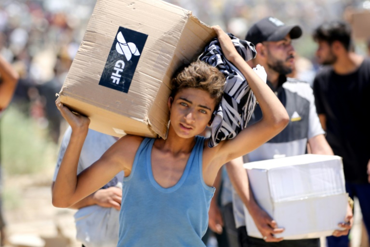 Un garçon porte une boîte d'aide humanitaire de la Fondation humanitaire de Gaza (GHF), venant d'un centre de distribution dans le centre de la bande de Gaza le 29 mai 2025 ( AFP / Eyad BABA )