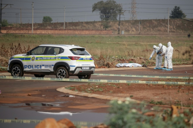 Des policiers sud-africains inspectent le lieu où le corps d'une femme a été découvert à Boksburg, à l'est de Johannesburg, le 17 septembre 2026 ( AFP / EMMANUEL CROSET )