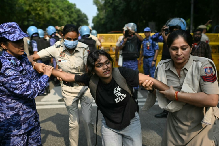 Du personnel de sécurité interpelle un étudiant militant lors d’une manifestation réclamant la démission du chef de la Commission électorale nationale, Gyanesh Kumar, à New Delhi, le 14 octobre 2026 ( AFP / Manan VATSYAYANA )