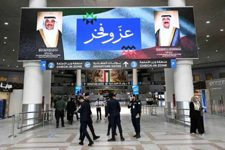 Des agents de sécurité koweïtiens sous un écran affichant les portraits de l'émir du Koweït, le cheikh Mech'al al-Ahmad al-Jaber al-Sabah (à droite), et du prince héritier koweïtien, le cheikh Sabah al-Khaled al-Hamad al-Sabah, accompagnés des mots "Fierté et Gloire", à l'aéroport international de Koweït City, le 1er juin 2026 ( AFP / YASSER AL-ZAYYAT )