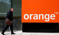 Un homme passe devant le logo Orange près de Paris