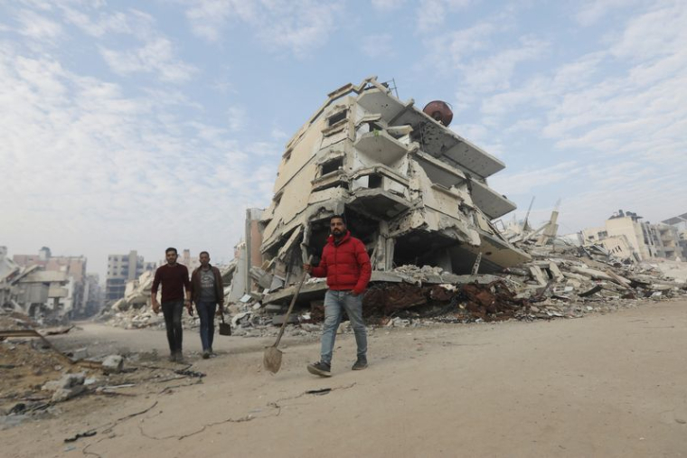 Des palestiniens marchent devant les décombres de bâtiments à Gaza