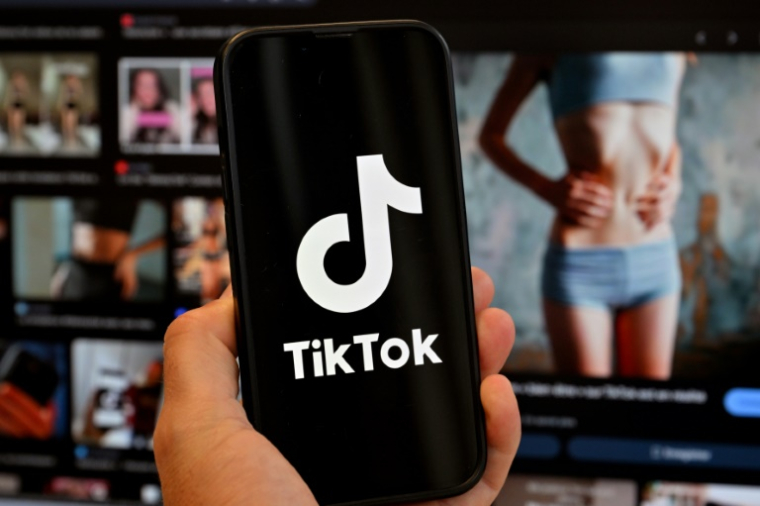 Photo d'illustration du 7 mai 2025 montrant le logo de Tik Tok sur un smartphone devant un écran affichant l'image d'une femme très mince, alors que la tendance "skinnytok" promouvant la minceur inquiète les experts ( AFP / Nicolas TUCAT )