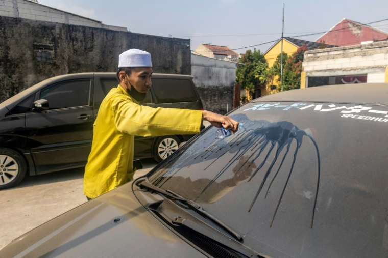 Un homme nettoie le pare-brise de sa voiture  couvert de cendre après l'éruption du volcan Anak Krakatoa à Bogor, dans la province de Java occidental, en Indonésie, le 6 septembre 2026 ( AFP / ADITYA Aji )