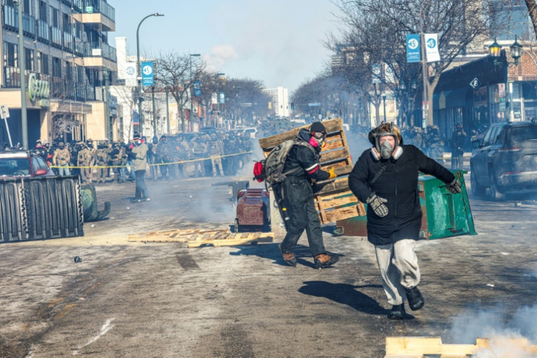 Des manifestants devant une barricade d'agents américains des forces de l'ordre fédérales après la mort d'un homme de 37 ans, tué par balle par des agents fédéraux, à Minneapolis (Minnesota), le 24 janvier 2026 ( AFP / Kerem YUCEL )