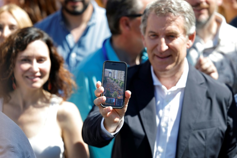 Le président du Parti populaire (PP), Alberto Nunez Feijoo, montre une image des manifestants sur son téléphone lors d'un rassemblement contre le gouvernement du Premier ministre socialiste Pedro Sanchez sur la Place d'Espagne, à Madrid, le 8 juin 2025 ( AFP / Thomas COEX )
