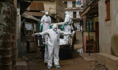 Des agents de la Croix-Rouge s'aspergent de désinfectant lors de l'évacuation du corps d'une victime présumée d'Ebola à Kampala, le 26 mai 2026 en Ouganda ( AFP / Badru KATUMBA )