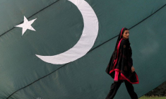 Une femme passe devant un drapeau national du Pakistan
