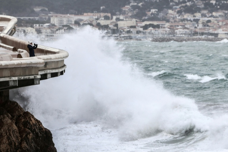 Une personne prend une photo depuis la Corniche tandis que les vagues s’écrasent contre le littoral à Marseille, le 12 février 2026 ( AFP / Thibaud MORITZ )