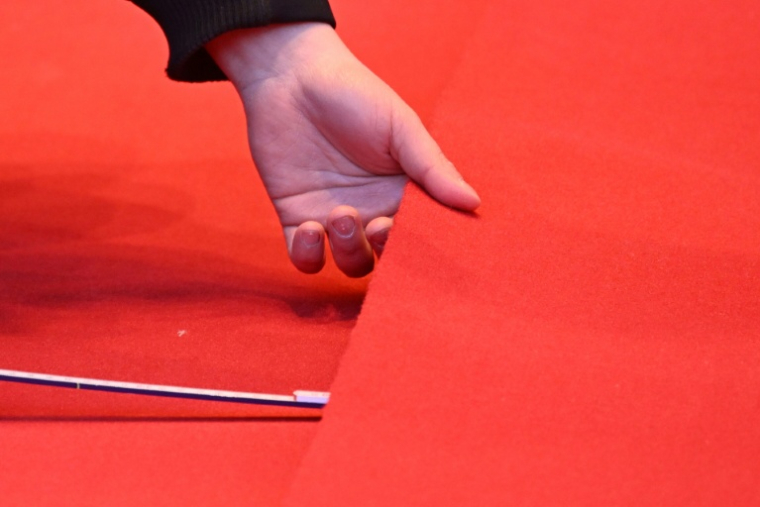 Une personne déroule le tapis rouge devant le Palais de la Berlinale, parmi les préparatifs pour le premier grand festival de cinéma de l'année en Europe, à Berlin, le 10 février 2026 ( AFP / RALF HIRSCHBERGER )