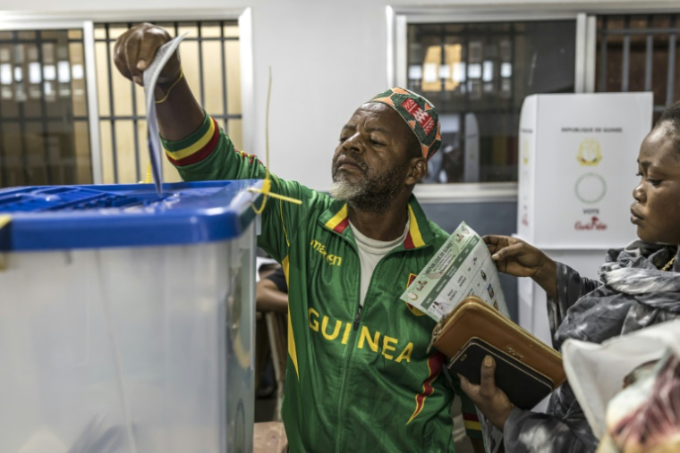 Un électeur dépose son bulletin dans l'urne dans un bureau de vote à Conakry, le 28 décembre 2025, lors de l'élection présidentielle guinéenne. ( AFP / PATRICK MEINHARDT )