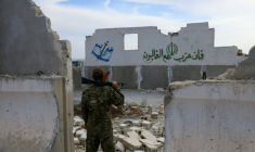 Un soldat syrien devant les ruines, portant des inscriptions anti-israéliennes, de la base iranienne abandonnée considérée comme la plus importante en Syrie avant la chute d'Assad, près d'Alep, le 4 décembre 2025 ( AFP / Bakr ALkasem )