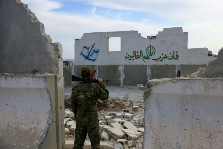 Un soldat syrien devant les ruines, portant des inscriptions anti-israéliennes, de la base iranienne abandonnée considérée comme la plus importante en Syrie avant la chute d'Assad, près d'Alep, le 4 décembre 2025 ( AFP / Bakr ALkasem )