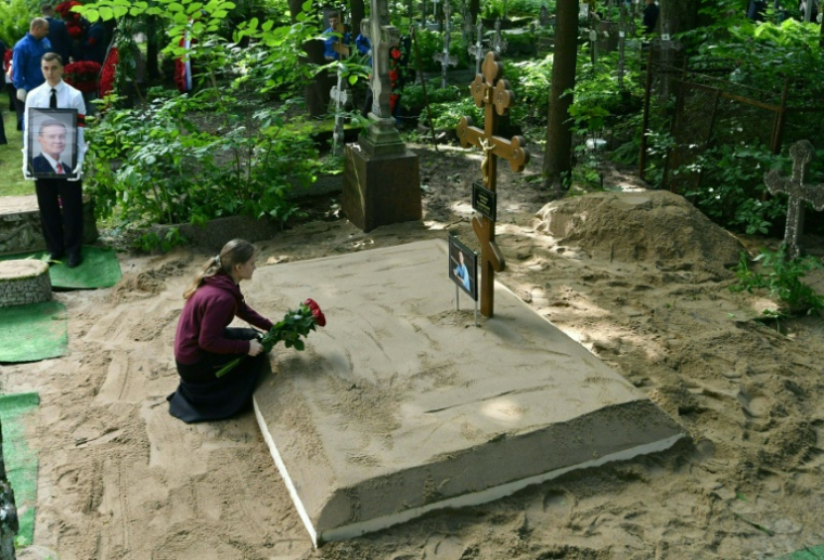 Une femme dépose des fleurs sur la tombe du ministre russe des Transports, Roman Starovoït, lors de ses funérailles à Saint-Pétersbourg, le 11 juillet 2025 à Saint-Pétersbourg ( AFP / Olga MALTSEVA )