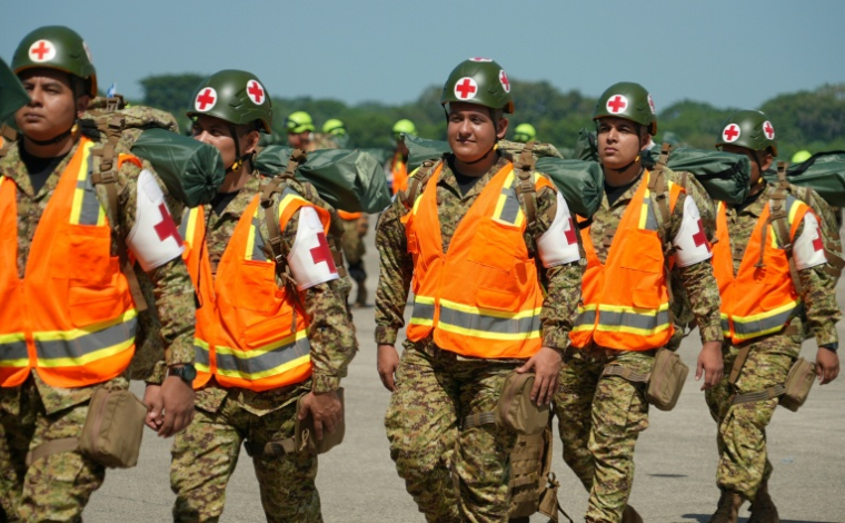 Des membres des forces armées salvadoriennes se préparent à embarquer dans un avion à destination du Venezuela, à la base aérienne de Comalapa, à San Luis Talpa, au Salvador, le 25 juin 2026 ( AFP / Rudy QUIROZ )