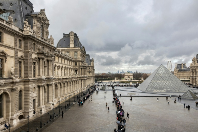 Des visiteurs font la queue, près de la pyramide conçue par l'architecte sino-américain Ieoh Ming Pei, pour entrer au musée du Louvre, le 19 novembre 2025 à Paris ( AFP / Sébastien DUPUY )