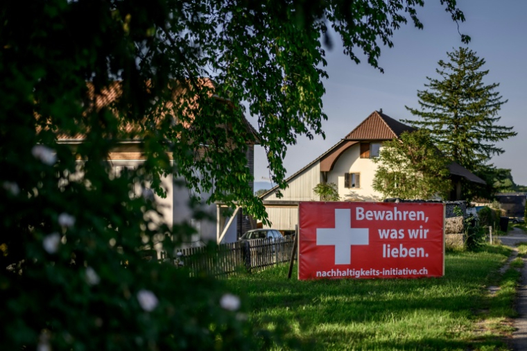Une banderole électorale en faveur d'une initiative visant à plafonner la population à 10 millions d'habitants, affichée en bord de route avec l'inscription en allemand "Préservons ce que nous aimons", près de Morat, le 26 mai 2026 en Suisse ( AFP / Fabrice COFFRINI )