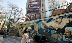 Un passante à Téhéran, devant une affiche hostile à Israël et aux Etats-Unis, le 25 février 2026 ( AFP / ATTA KENARE )