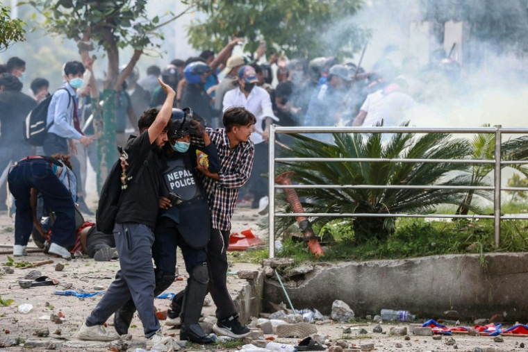 Un policier blessé est porté par des manifestants lors de heurts avec la police, le 8 septembre 2025 à Katmandou, au Népal ( AFP / Prabin RANABHAT )