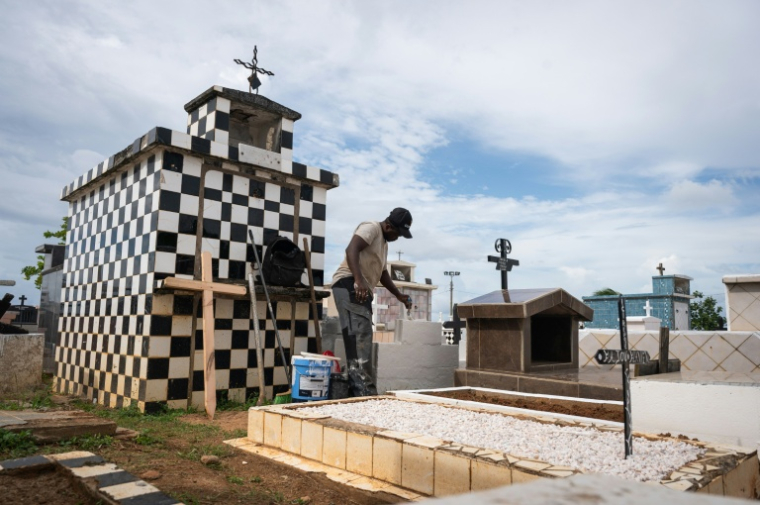 Un homme repeint une tombe dans le cimetière de Sainte-Rose-de-Lima, à Sainte-Rose en Guadeloupe, le 31 octobre 2025 ( AFP / Carla Bernhardt )