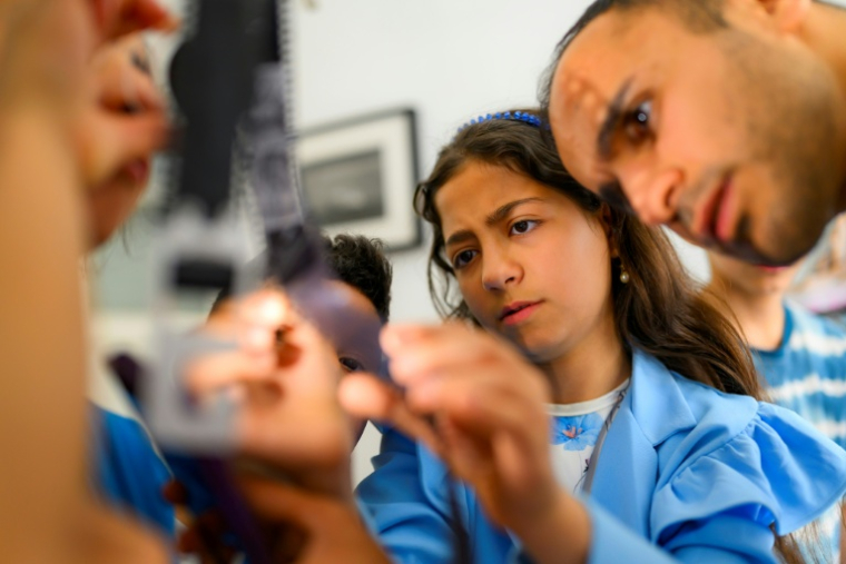 Le photographe syrien Serbest Salih (D) travaille avec des enfants lors d'un atelier organisé dans le cadre du projet "Fotohane Darkroom" à Mardin, dans le sud-est de la Turquie, le 13 juin 2026 ( AFP / Yasin AKGUL )