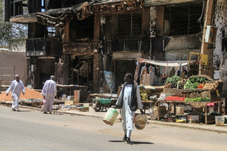 Des hommes passent devant un bâtiment partiellement détruit dans la capitale soudanaise Khartoum, le 15 avril 2026 ( AFP / Ebrahim Hamid )