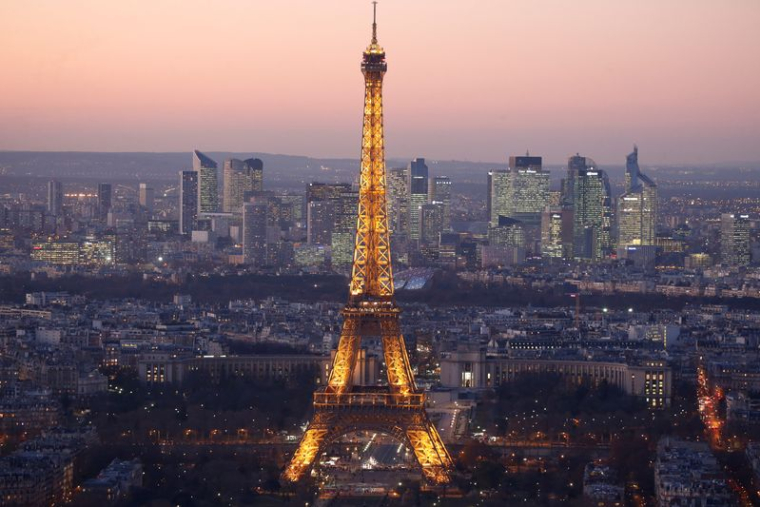 Une vue générale montre la Tour Eiffel illuminée et la ligne d'horizon du quartier d'affaires de La Défense de nuit à Paris