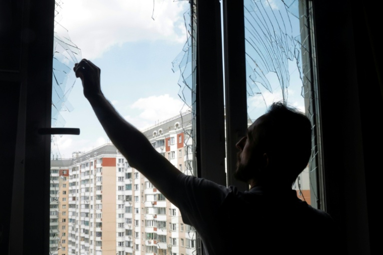 Un habitant retire des éclats de verre d’une fenêtre brisée dans un immeuble d'habitation après une attaque aérienne à Krasnogorsk, dans la région de Moscou, le 17 mai 2026 ( AFP / TATYANA MAKEYEVA )