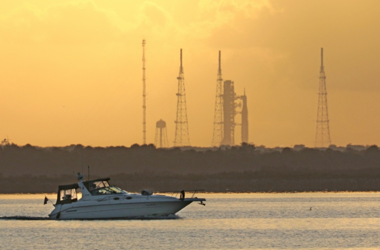 Un bateau passe au large de la fusée SLS Artémis 2 de la Nasa au Centre spatial Kennedy, au lever du soleil à Cap Canaveral, en Floride, le 1er avril 2026 ( AFP / Gregg Newton )
