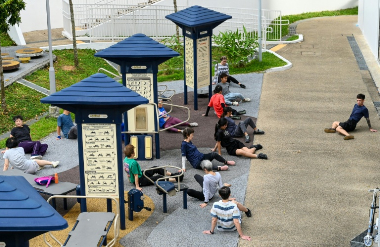 Le coach Tan Shie Boon (d) guide des personnes âgées lors d'une séance d'entraînement de parkour à Singapour, le 17 mars 2026 ( AFP / Roslan RAHMAN )
