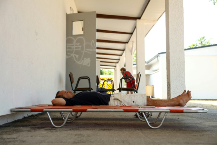 Un homme se repose sur un lit de camp à l'extérieur d'une salle au Porge, en Gironde, ouverte pour les personnes évacuées en raison de l'incendie qui sévit au nord du bassin d'Arcachon, le 23 juillet 2026 ( AFP / ROMAIN PERROCHEAU )