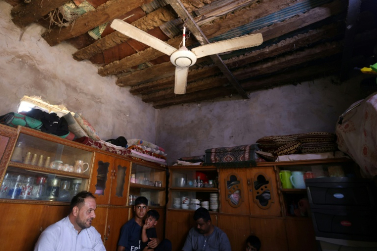Une famille irakienne sous un ventilateur, à Hilla, dans le centre de l'Irak, le 10 août 2025 ( AFP / AHMAD AL-RUBAYE )