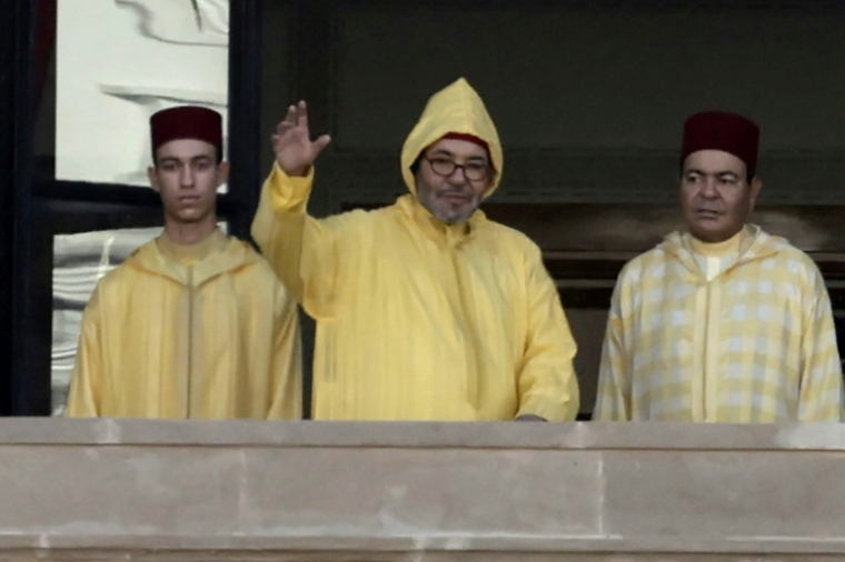 Le roi du Maroc Mohammed VI (c), accompagné de son fils, le prince héritier Moulay Hassan (g), apparaît sur le balcon du siège du Parlement à Rabat, le 10 octobre 2025 ( AFP / Abdel Majid BZIOUAT )
