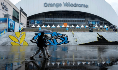 Des piétons abrités sous un parapluie passent devant le stade Vélodrome, où le match de L1 OM-PSG a été reporté de 24 heures en raison des intempéries, le 21 septembre 2025 à Marseille ( AFP / Miguel MEDINA )