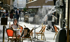 Une jeune fille assise à la terrasse d'un marchand de glaces, sur laquelle un ventilateur-brumisateur a été installé pour se protéger de la chaleur à Milan en Italie, le 27 mai 2026 ( AFP / Stefano RELLANDINI )