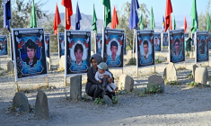 Une femme afghane et un enfant assis dans un cimetière des membres de la communauté hazara, à Tapa-e-Shuhada (la colline des Martyrs), Kaboul, le 25 août 2026 ( AFP / Wakil KOHSAR )