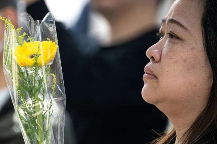 Une femme se recueille le 29 novembre 2025 devant le complexe résidentiel de Wang Fuk Court à Hong Kong  la suite de l’incendie meurtrier survenu trois jours auparavant ( AFP / Philip FONG )