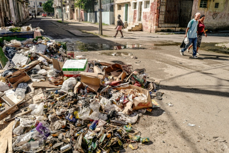 Des habitants du quartier de Jesus Maria, à La Havane, passent devant un monticule de déchets, le 20 novembre 2025 ( AFP / ADALBERTO ROQUE )